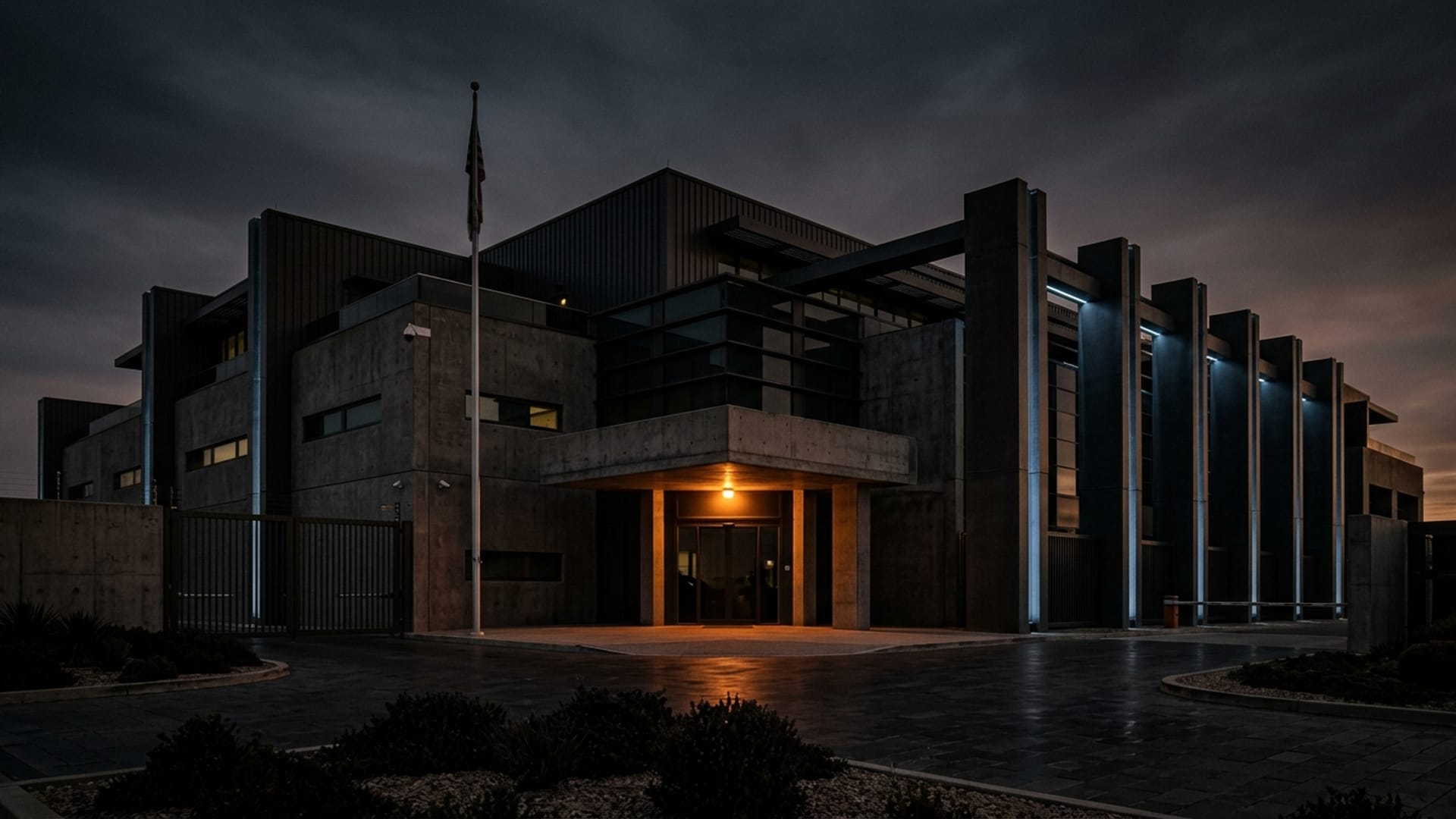 Fortified corporate facility at dusk, illuminated by a single amber beacon — representing Guardian Group Advisors' security consulting practice.